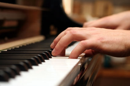 Piano keyboard with hands playing the piano