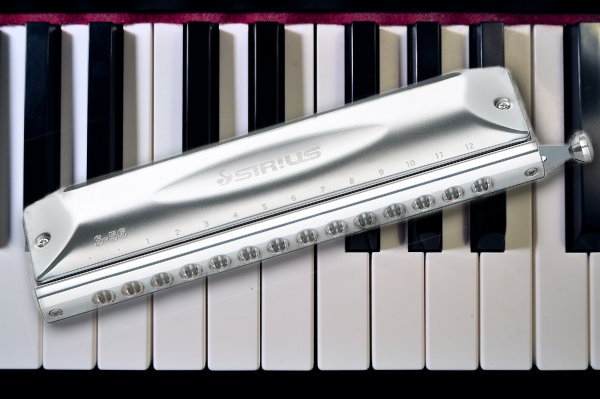 A harmonica sitting on top of a piano keyboard